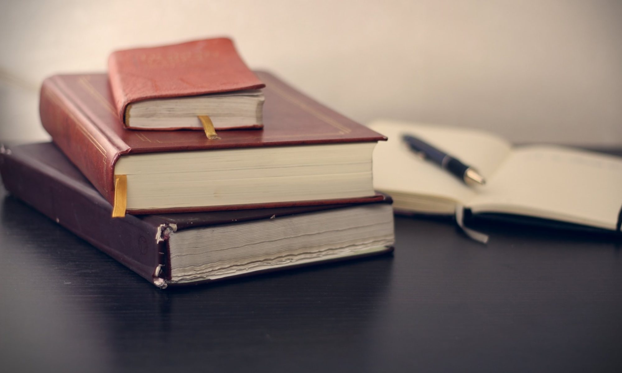 selective focus photography of three books beside opened notebook